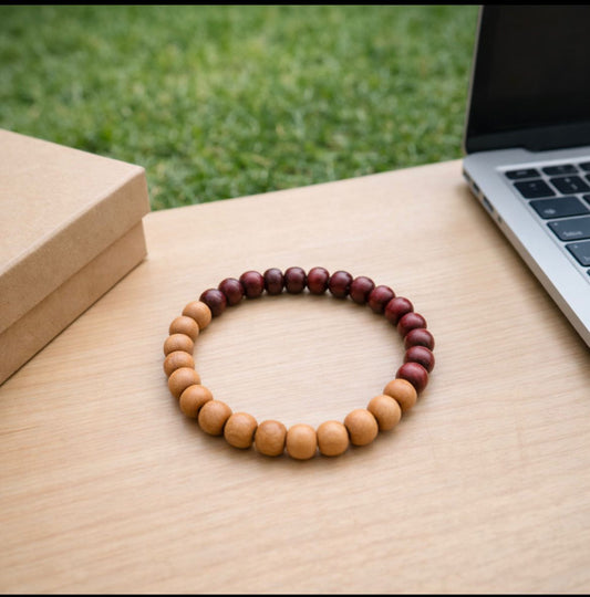 Wooden beaded bracelet on a wooden surface with a laptop and grass in the background