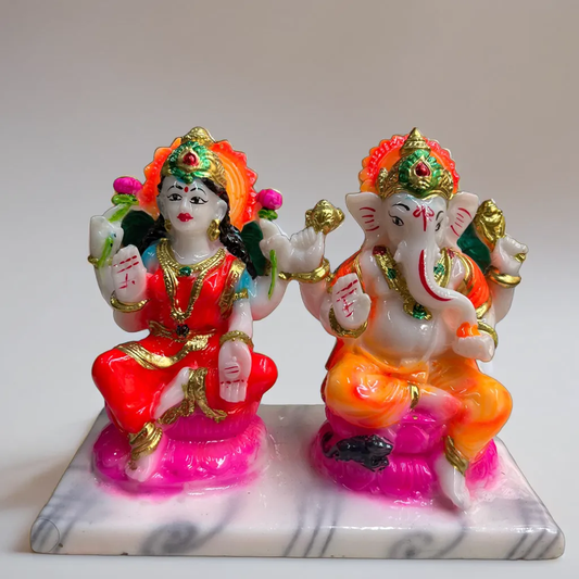 Colorful statues of a deity and a elephant-headed figure on a marble base.