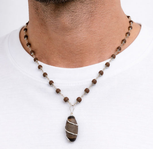 Necklace with brown beads and a pendant worn by a person on a white background